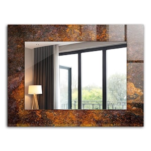 Pode incluir: Um espelho retangular com uma moldura marrom, laranja e ferrugem. A moldura tem um aspecto texturizado e marmorizado. O espelho reflete uma sala com uma janela e uma lâmpada.