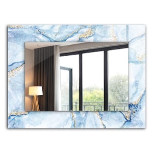 Op de afbeelding: Een rechthoekige spiegel met een blauw en gouden abstract aquarelontwerp frame. De spiegel reflecteert een kamer met een raam en een lamp.