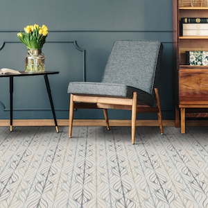 Könnte beinhalten: Ein Wohnzimmer mit einer blauen Wand, einem Holzstuhl, einem schwarzen Beistelltisch mit einer Vase mit gelben Blumen und einem Holzbuchregal. Der Boden ist mit einem gemusterten Teppich mit geometrischem Design bedeckt.