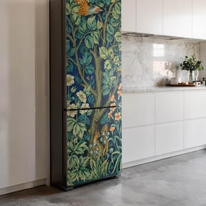 Op de afbeelding: Een koelkast met een decoratieve wrap met een gedetailleerd boom- en bladerdesign in tinten blauw, groen en bruin. Het kunstwerk bevat een vogel, een eekhoorn en bloemen, wat een op de natuur geïnspireerde esthetiek creëert.
