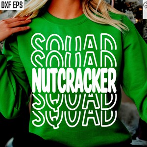 May include: Green sweatshirt with white text that reads "Squad Nutcracker Squad" in a layered, stacked design.