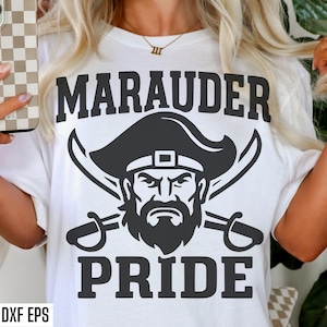 May include: White t-shirt with a black graphic design. The design features the word "MARAUDER" above a pirate face with crossed swords and the word "PRIDE" below. The image also includes "SVG PNG DXF EPS" text.