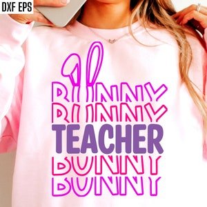 May include: Pink sweatshirt with a graphic design that says "Bunny Teacher Bunny Bunny" in a layered, stacked font with pink and purple colors.
