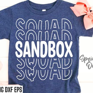 May include: A blue t-shirt with the text "Sandbox Squad" in white outlined letters. The text is repeated in a stacked pattern with each word slightly offset from the one above it.
