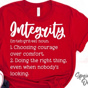 May include: Red t-shirt with white text that reads "Integrity {in-teh-grit-ee} noun. 1. Choosing courage over comfort. 2. Doing the right thing, even when nobody's looking." and "Springhill Digitals" in the bottom right corner.