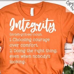 May include: Orange t-shirt with white text that reads "Integrity {in-teh-grit-ee} noun. 1. Choosing courage over comfort. 2. Doing the right thing, even when nobody's looking."