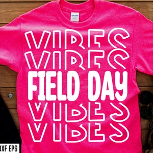 May include: Pink t-shirt with white text that reads "Vibes Vibes Field Day Vibes Vibes".