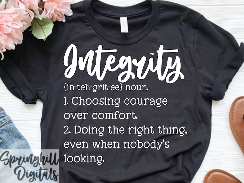 May include: Black t-shirt with white text that reads "Integrity {in-teh-grit-ee} noun. 1. Choosing courage over comfort. 2. Doing the right thing, even when nobody's looking."