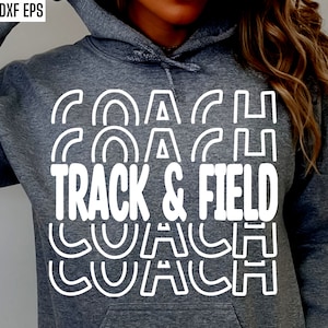 Könnte beinhalten: Ein grauer Hoodie mit dem Text "COACH TRACK & FIELD COACH" in Weiß, wiederholt in einem gestapelten, geschwungenen Design.