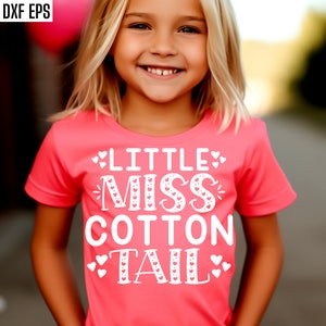 Peut inclure: Un t-shirt rose avec le texte "Little Miss Cotton Tail" en blanc avec de petits cœurs autour du texte.