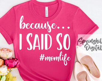 May include: Pink t-shirt with the text "because... I SAID SO #momlife" in white. The shirt is photographed on a white surface with a bouquet of flowers and a pair of pink shoes.