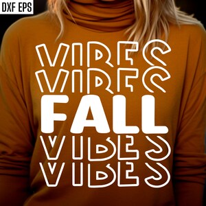 K&ouml;nnte beinhalten: Ein senfgelbes Langarmshirt mit dem Text "Fall Vibes" in wei&szlig;en umrandeten Buchstaben.