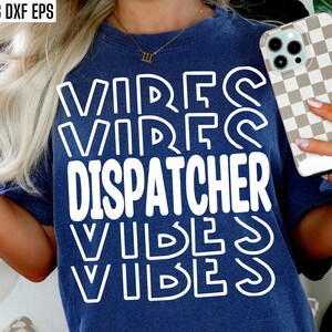 Könnte beinhalten: Ein blaues T-Shirt mit dem Text "VIBES DISPATCHER VIBES" in weißen umrandeten Buchstaben.