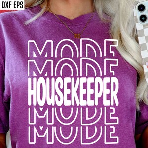 May include: Purple t-shirt with white text that reads "Mom Mode Housekeeper Mom Mode" in a retro font.