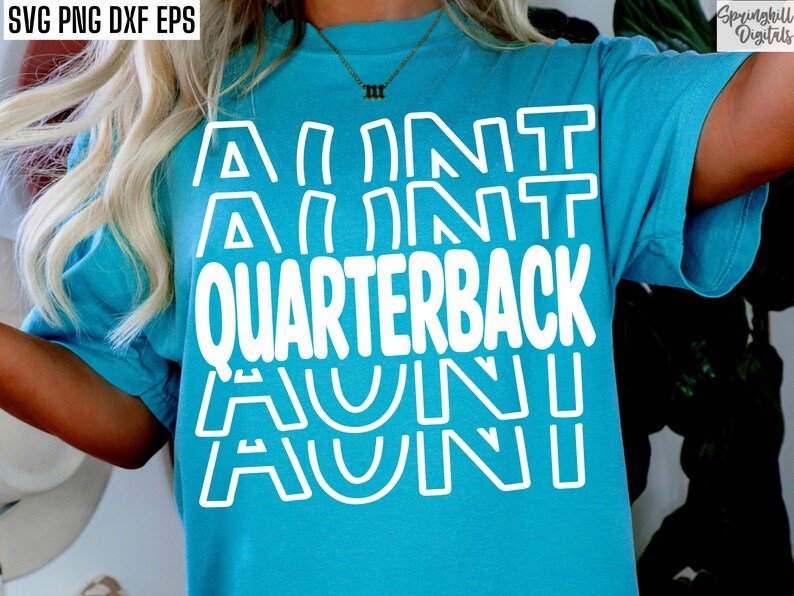 Op de afbeelding: Een turquoise blauw t-shirt met de tekst "AUNT QUARTERBACK AUNT" in witte omrande letters.