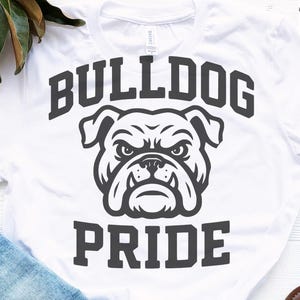 May include: White t-shirt with a bulldog graphic. The design features the words "BULLDOG PRIDE" in a bold, dark gray font, with a detailed bulldog illustration centered above the word "PRIDE".