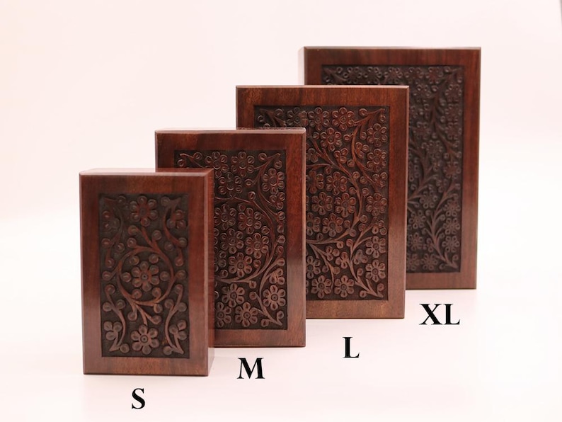 May include: Four wooden boxes of varying sizes, labeled S, M, L, and XL. Each box is a rich brown color and features a detailed floral carving on the front. The boxes are arranged in a row, showcasing the different sizes.