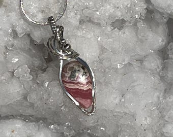 May include: A silver wire wrapped pendant featuring a pink and white banded agate gemstone. The pendant is displayed on a white background.