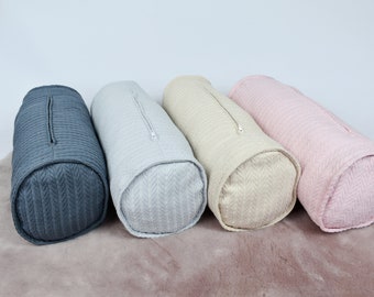 May include: Four cylindrical pillows in different colors: dark gray, light gray, beige, and pink. The pillows have a herringbone pattern and a zipper closure.