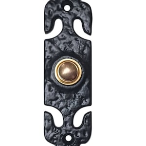 Pode incluir: Botão de campainha preto com um botão dourado no centro. A campainha tem um design decorativo e ornamentado com uma parte superior e inferior pontiagudas.