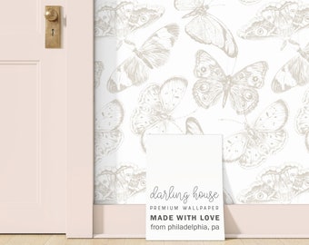 May include: White wallpaper with a repeating pattern of gray butterflies. The wallpaper is shown on a wall in a room with a white door and a light wood floor. A white sign with the text "darling house PREMIUM WALLPAPER MADE WITH LOVE from philadelphia, pa" is on the floor in front of the wall.