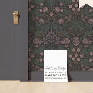 May include: A white sign with the text "darling house PREMIUM WALLPAPER MADE WITH LOVE from philadelphia, pa" against a dark brown floral wallpaper background.