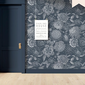May include: A blue wall with a white floral pattern wallpaper. A white sign with the text "DARLING HOUSE premium WALLPAPER MADE WITH LOVE from PHILADELPHIA, PA" is hanging on the wall.