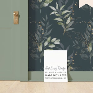 May include: A white sign with the text "darling house PREMIUM WALLPAPER MADE WITH LOVE from philadelphia, pa" on a dark blue background with a gold and green leaf pattern.