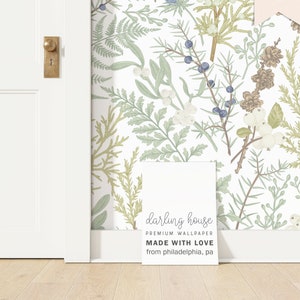 May include: A white background with a green and blue floral pattern. The pattern features various types of leaves, berries, and flowers. The text "darling house PREMIUM WALLPAPER MADE WITH LOVE from philadelphia, pa" is printed on a white rectangle.