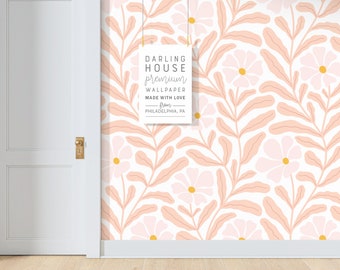 May include: A white wall with a pink and yellow floral wallpaper pattern. A white door is on the left side of the image. A sign with the text "DARLING HOUSE premium WALLPAPER MADE WITH LOVE from PHILADELPHIA, PA" is hanging on the wall.