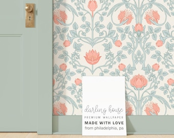 May include: A white sign with the text "darling house PREMIUM WALLPAPER MADE WITH LOVE from philadelphia, pa" on a light wood floor in front of a wall with a floral wallpaper pattern in shades of pink, green, and white.