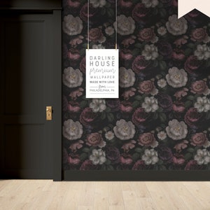 May include: A black and white sign with the text "DARLING HOUSE premium WALLPAPER MADE WITH LOVE from PHILADELPHIA, PA" hanging on a dark floral wallpaper with pink and white flowers.