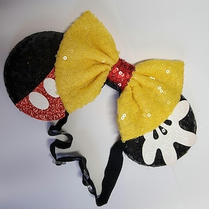 May include: Black and red sequined Minnie Mouse ears with a yellow bow and a black headband.