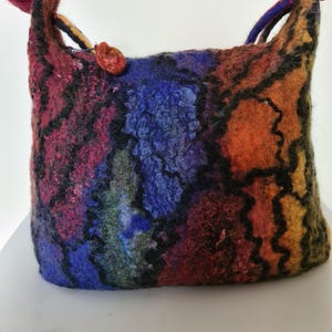 May include: A colorful felted tote bag with a black, wavy design. The bag has a red, orange, yellow, blue, and green color scheme.