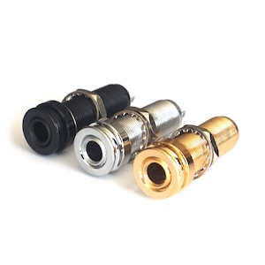 May include: Three guitar output jacks in black, silver, and gold. The jacks are designed to be mounted on a guitar or other instrument.
