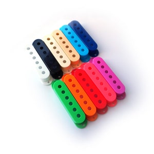 Peut inclure: Assortiment de 12 caches de micros de guitare en plastique de couleurs différentes. Les caches sont disposées en arc-en-ciel, avec le cache blanc en haut et le cache vert en bas.