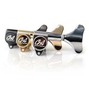 Pode incluir: Três afinadores de guitarra em preto, dourado e prateado. Cada afinador tem uma face circular com o texto "CA GUITAR ANATOMY". As cravelhas estão em fila, com a prateada à direita.
