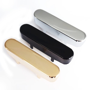 May include: Three guitar pickup covers in different finishes: gold, black, and chrome. The covers are made of metal and have a smooth, polished finish.