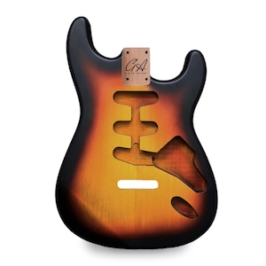 Könnte beinhalten: Ein Gitarrenkorpus mit Sunburst-Finish, das von Schwarz zu Orange und Gelb übergeht. Der Korpus hat Aussparungen für Tonabnehmer und Bedienelemente. Eine Holzhalsaussparung mit dem Text "CA Guitar Anatomy" ist angebracht.