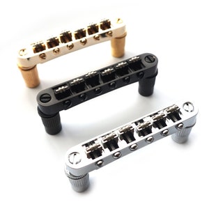 May include: Three guitar bridges in different finishes: gold, black, and chrome. Each bridge has six adjustable saddles.