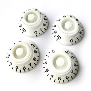 May include: Four white plastic knobs with black numbers and a white centre knob. The knobs are numbered 1 through 10.