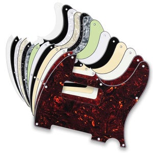 May include: A collection of electric guitar pickguards arranged in a fan shape. The pickguards feature various finishes including solid white, solid black, cream, mint green, and marbled patterns in red, grey, and black with pre-drilled holes.