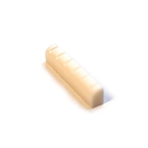 May include: A cream-coloured guitar nut with five string slots. The rectangular piece is made of a solid, smooth material and is designed to fit on a guitar's neck. The nut is a replacement part for stringed instruments.