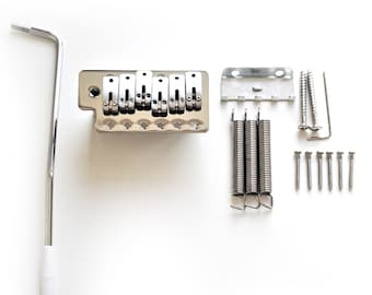 Puede incluir: Un puente de guitarra eléctrica cromado con seis selletas, un brazo de trémolo, tres muelles y tornillos de montaje. El puente está diseñado para una guitarra de seis cuerdas.