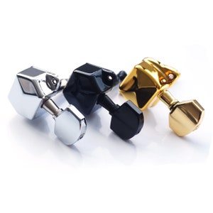 Puede incluir: Tres clavijas de afinación de guitarra en acabados plateado, negro y dorado. Cada clavija tiene una forma hexagonal con una parte superior redondeada.