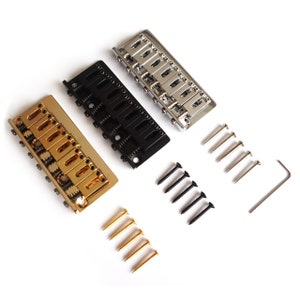 Puede incluir: Tres puentes de guitarra en oro, negro y cromo con tornillos de montaje y una llave Allen.