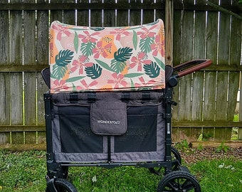 May include: A black wagon with a tropical print canopy. The wagon has a black frame and wheels, and the canopy is made of a lightweight fabric with a floral design. The wagon is labeled "Wonderfold" on the side.