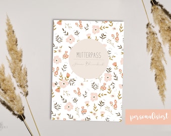 Könnte beinhalten: Ein weißes Notizbuch mit einem Blumenmuster und einem rosa Kreis mit dem Text "MUTTERPASS" und "Hanna Blank" in Schwarz. Der Text "personalisiert" ist in Weiß auf rosa Hintergrund am unteren Rand des Bildes.