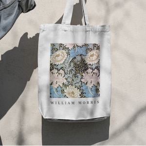 May include: White canvas tote bag with a floral print featuring blue, white, and pink flowers. The bag has black handles and the text "WILLIAM MORRIS" printed on the bottom.