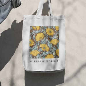 May include: White canvas tote bag with a floral print featuring yellow flowers and green leaves on a brown background. The text "WILLIAM MORRIS" is printed in black at the bottom of the bag.